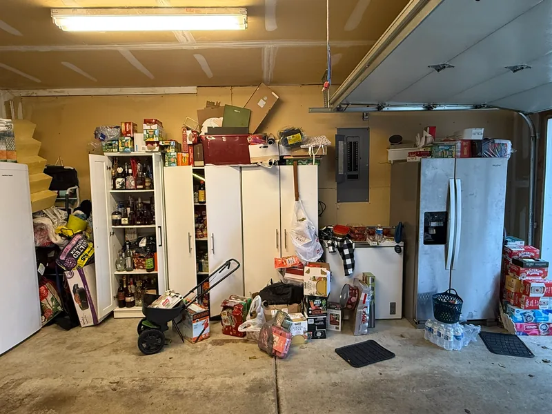 Cabinet and refrigerator wall before, with goods piled around cabinets and appliances