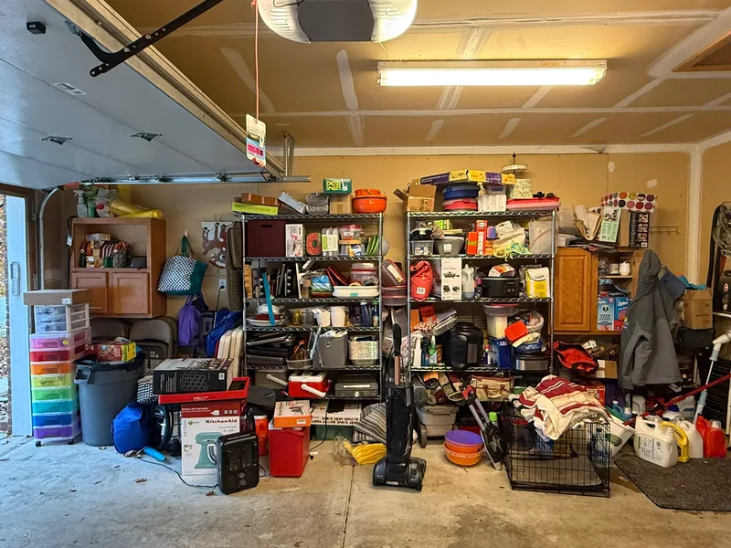 Shelving wall before, with mixed items on shelves and across the floor